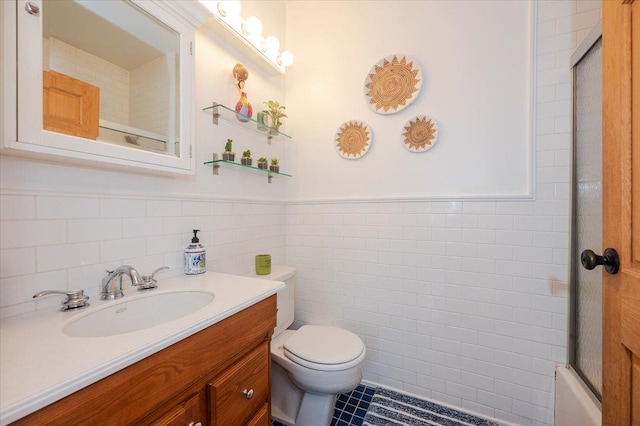 full bathroom with tile patterned floors, toilet, shower / bath combination with glass door, tile walls, and vanity