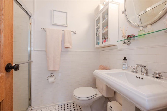 bathroom with toilet, a shower with shower door, sink, tile walls, and a baseboard radiator