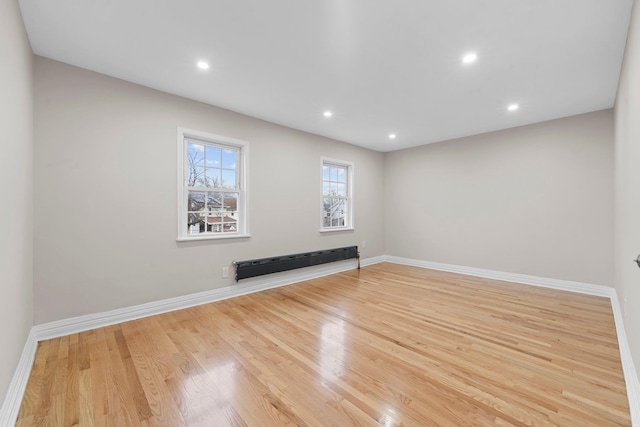 empty room with a baseboard radiator and light hardwood / wood-style flooring