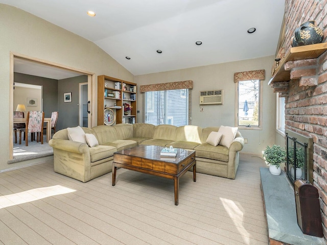 living room with a wall mounted air conditioner, vaulted ceiling, a brick fireplace, and light hardwood / wood-style flooring