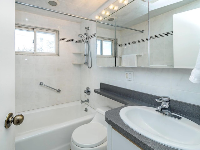 full bathroom with tiled shower / bath, tile walls, backsplash, vanity, and toilet