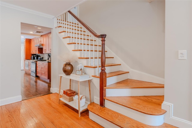 stairs featuring hardwood / wood-style floors and ornamental molding