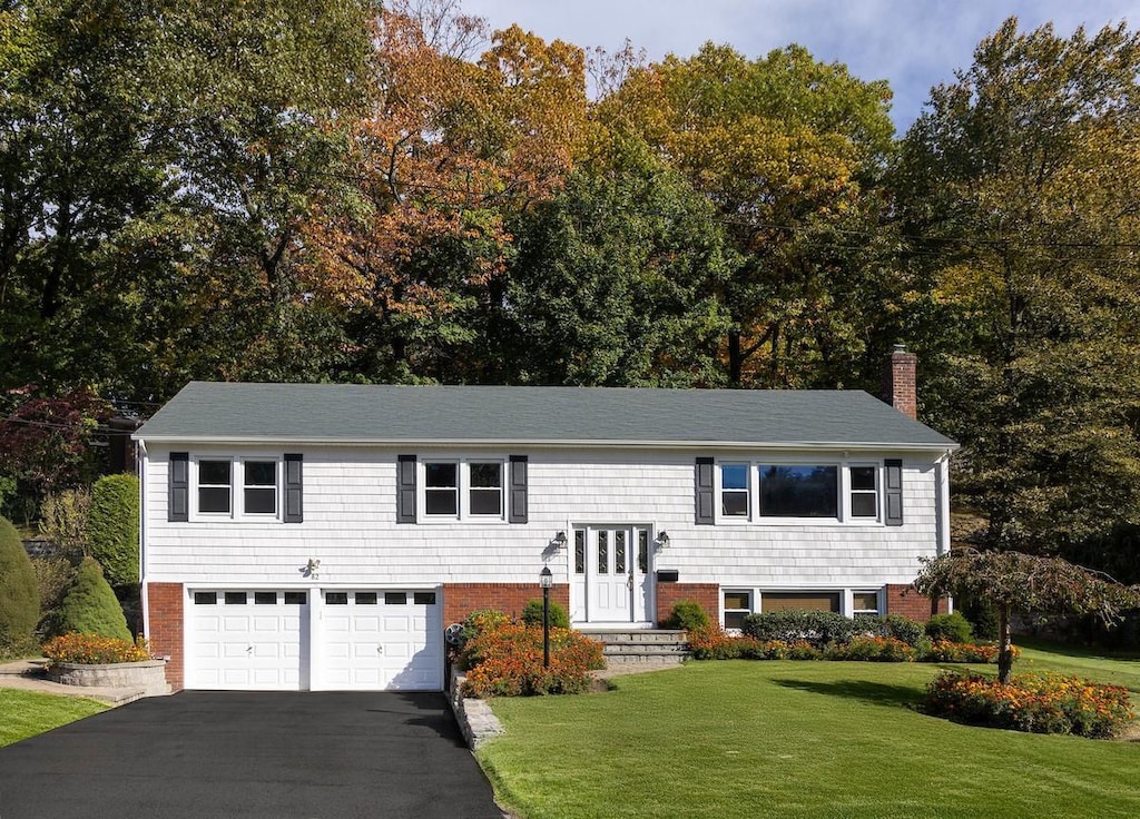 raised ranch featuring a garage and a front lawn