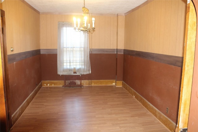 unfurnished dining area featuring light hardwood / wood-style flooring, radiator, and an inviting chandelier