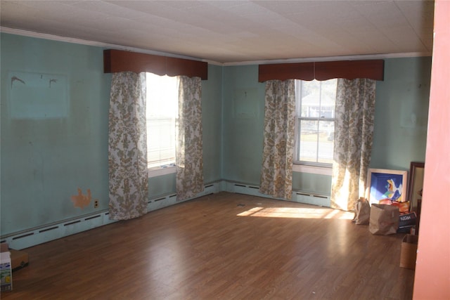 unfurnished room with a baseboard radiator, wood-type flooring, and crown molding