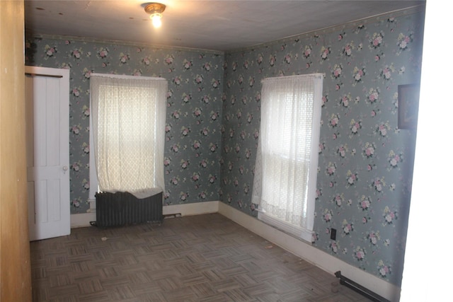 empty room with dark parquet flooring and radiator