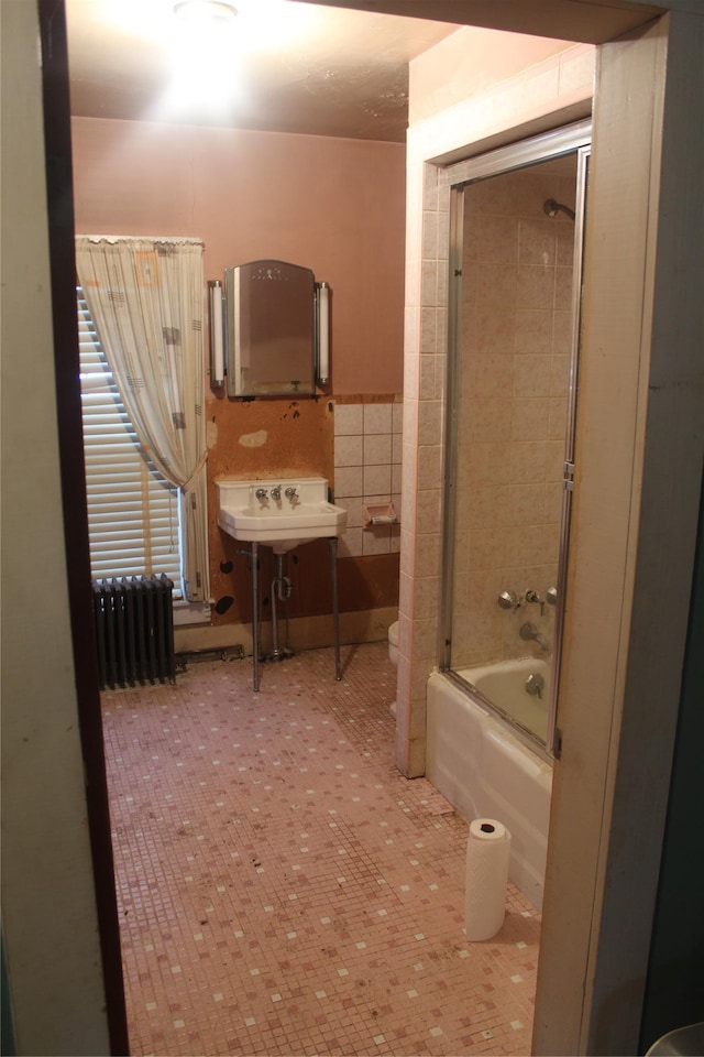 bathroom featuring combined bath / shower with glass door, radiator, tile walls, and tile patterned flooring