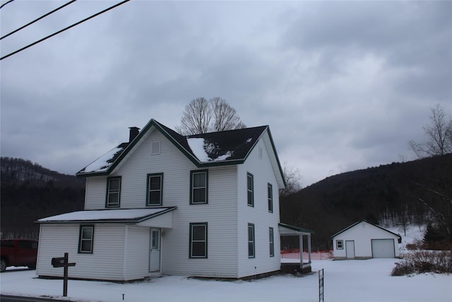 view of front property featuring a garage, an outbuilding, and a mountain view