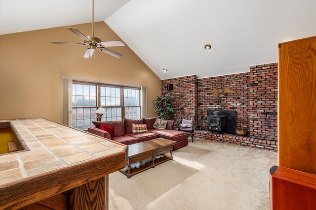 carpeted living room featuring high vaulted ceiling, a wood stove, and ceiling fan