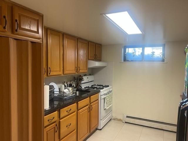 kitchen featuring white gas range oven, a baseboard heating unit, and light tile patterned flooring