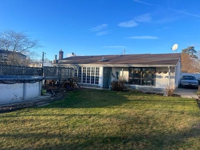 rear view of house with a covered pool and a lawn