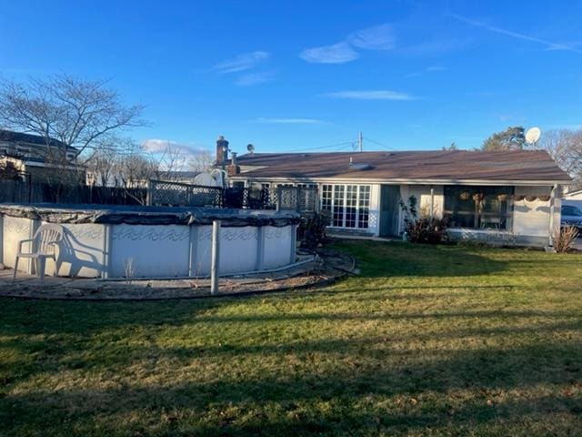 back of property with a covered pool and a yard