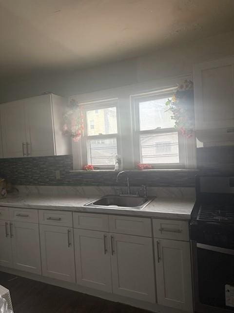 kitchen with stainless steel range, white cabinetry, dark hardwood / wood-style flooring, tasteful backsplash, and sink