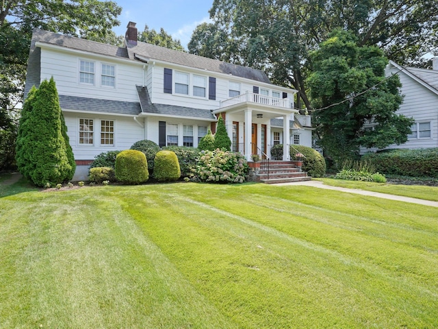 view of front of property featuring a balcony and a front yard