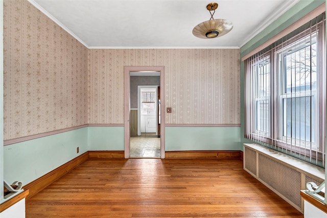 spare room with radiator heating unit, hardwood / wood-style flooring, and ornamental molding