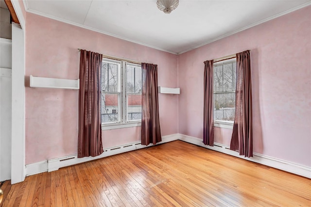 spare room with hardwood / wood-style floors, baseboard heating, and crown molding