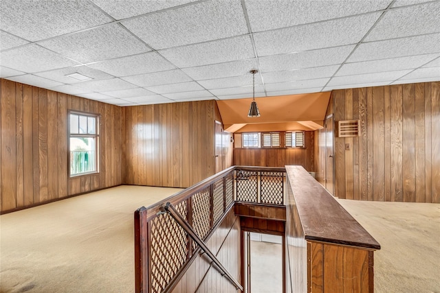 bonus room featuring light carpet and wooden walls