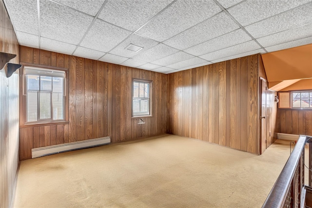 carpeted empty room featuring a baseboard radiator and wood walls