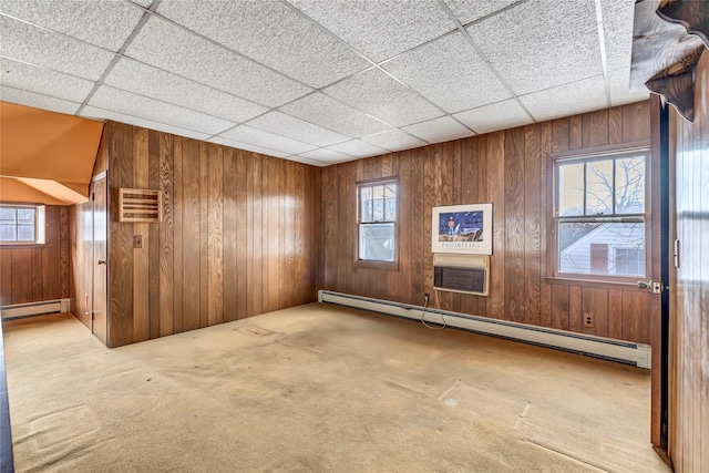 carpeted empty room with wood walls, a baseboard heating unit, and a wall unit AC