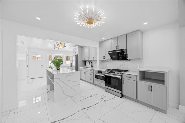 kitchen with light stone countertops, hanging light fixtures, gray cabinetry, and stainless steel appliances