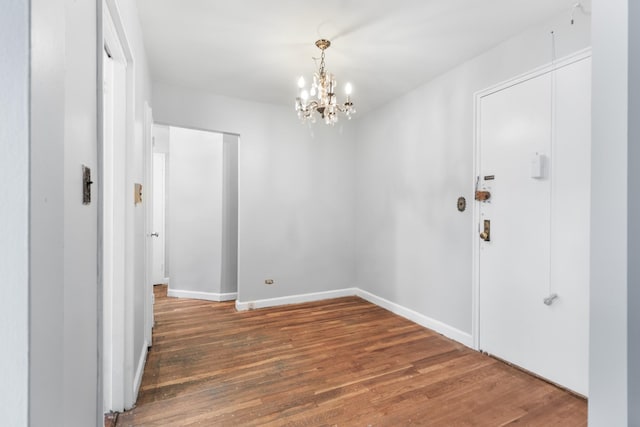 empty room featuring a notable chandelier and dark hardwood / wood-style flooring