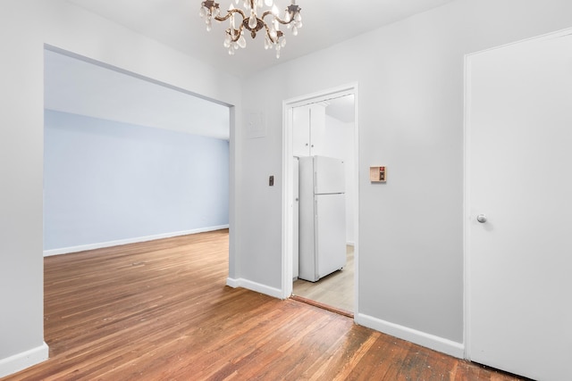 empty room featuring hardwood / wood-style floors and a chandelier