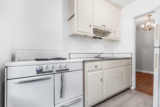 kitchen with sink, decorative light fixtures, white cabinets, range with two ovens, and light hardwood / wood-style floors