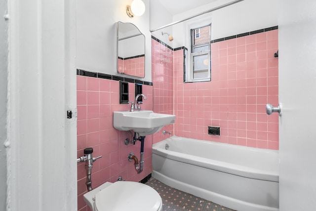 full bathroom featuring tiled shower / bath, tile patterned floors, sink, tile walls, and toilet