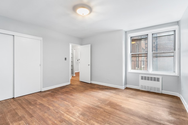 unfurnished bedroom with a closet, light hardwood / wood-style flooring, and radiator