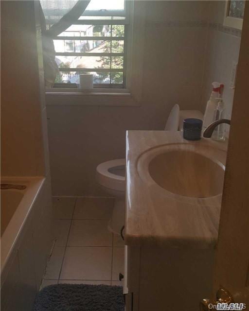 bathroom featuring vanity, toilet, a healthy amount of sunlight, and tile patterned flooring