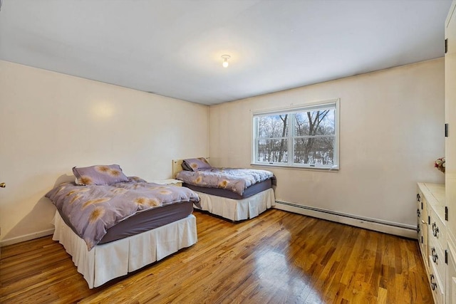 bedroom featuring baseboard heating and light hardwood / wood-style flooring