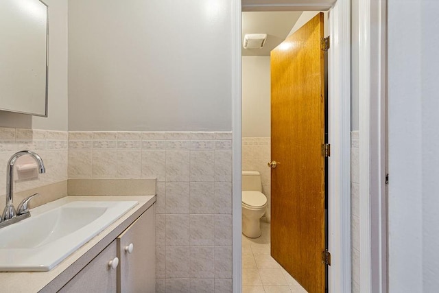 bathroom with vanity, toilet, tile patterned flooring, and tile walls