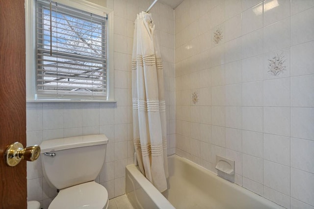 bathroom featuring toilet, shower / bath combo with shower curtain, and tile walls