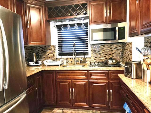 kitchen with light stone counters, sink, tasteful backsplash, and appliances with stainless steel finishes