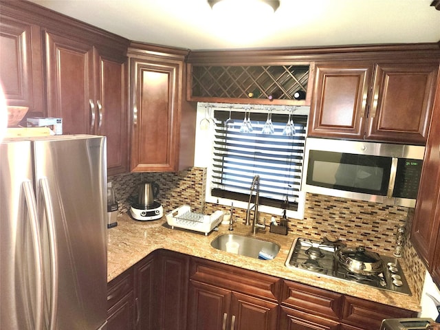 kitchen featuring light stone counters, sink, backsplash, and appliances with stainless steel finishes