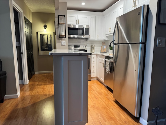 kitchen featuring stainless steel appliances, a kitchen island, white cabinets, and light hardwood / wood-style flooring