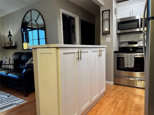 kitchen featuring appliances with stainless steel finishes, backsplash, white cabinets, and light hardwood / wood-style floors