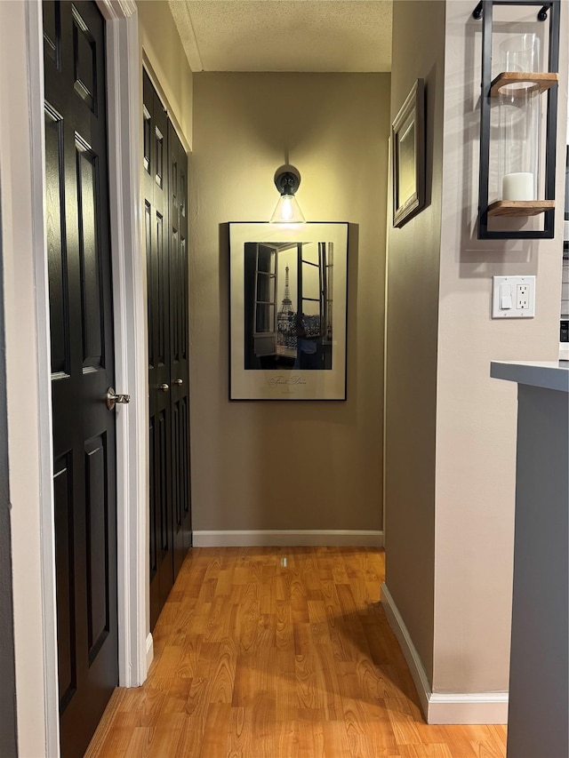 hallway featuring light hardwood / wood-style floors and a textured ceiling