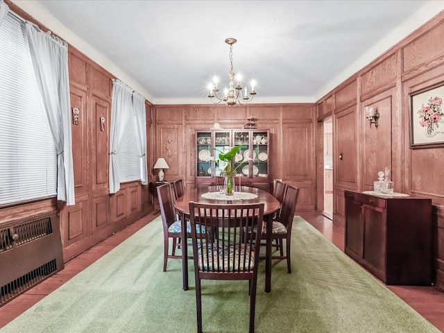 dining room with radiator heating unit, a notable chandelier, and wooden walls