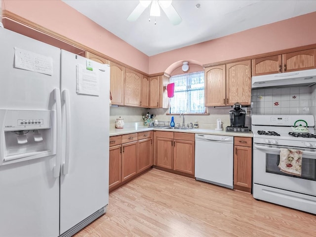 kitchen with sink, white appliances, ceiling fan, tasteful backsplash, and light hardwood / wood-style floors