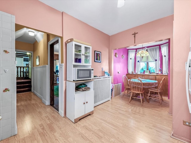 kitchen with radiator, light hardwood / wood-style flooring, and decorative light fixtures