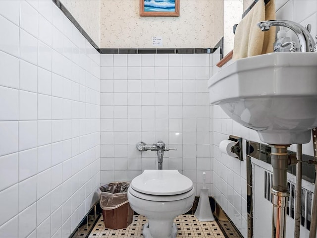 bathroom featuring sink, toilet, tile patterned flooring, and tile walls