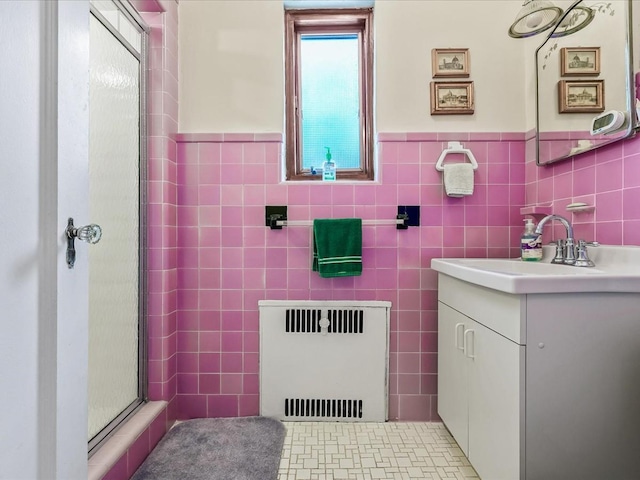 bathroom featuring radiator heating unit, tile patterned flooring, tile walls, and vanity