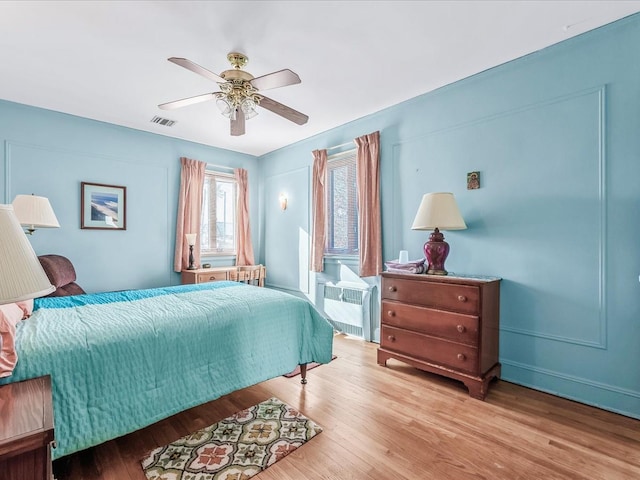 bedroom with radiator, light hardwood / wood-style floors, and ceiling fan