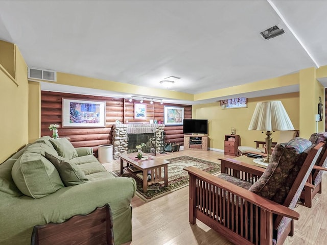 living room featuring log walls, a fireplace, and light wood-type flooring