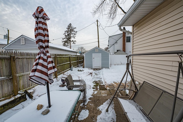 yard layered in snow featuring a storage shed