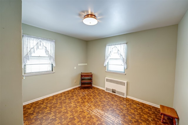 spare room featuring radiator heating unit and dark parquet floors