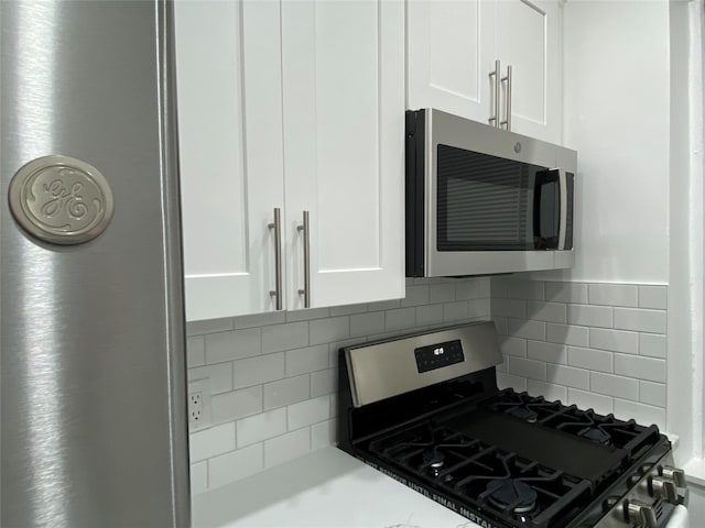 kitchen featuring white cabinets, stainless steel appliances, and backsplash