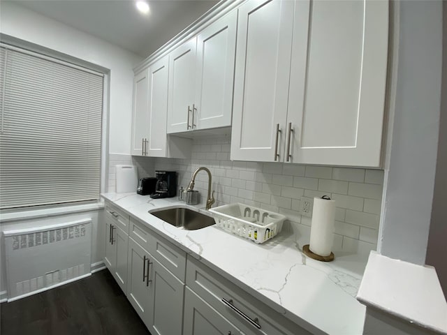 kitchen with radiator, sink, white cabinets, decorative backsplash, and light stone counters