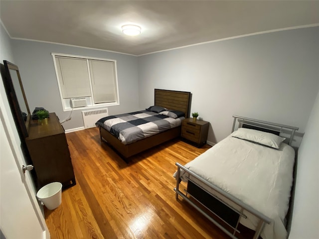 bedroom featuring crown molding, wood-type flooring, and radiator